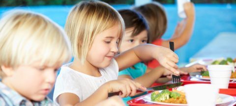 Elementary Pupils Enjoying Healthy Lunch In Cafeteria